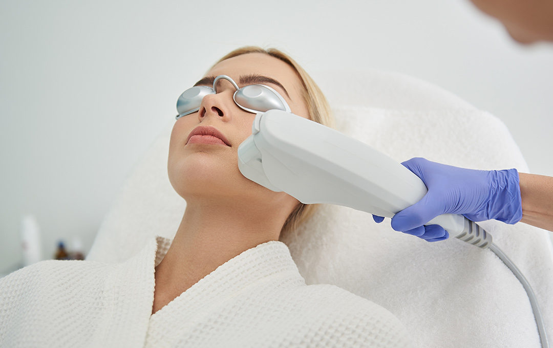 Woman lying back in a chair receiving a collagen stimulation treatment while wearing eye protection.