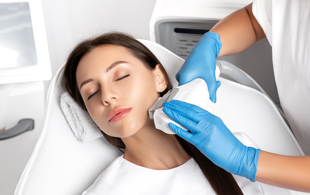 Woman lying back on a chair, while receiving an IPL treatment on her jawline with her eyes closed.